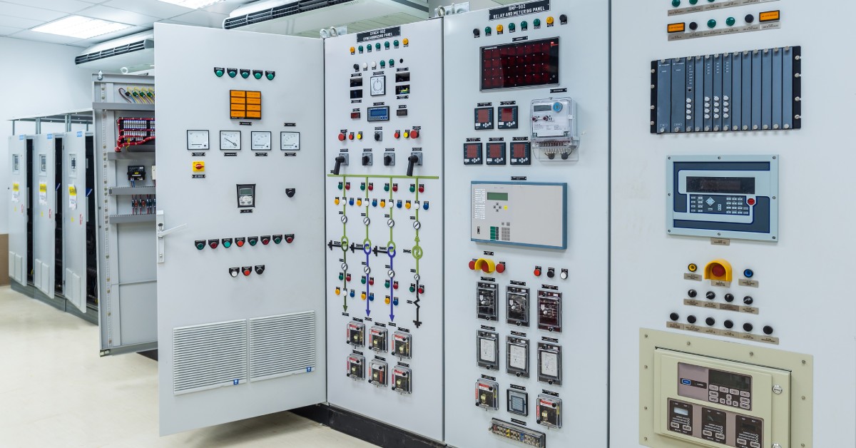 A large electric control panel with multiple doors, each one with different buttons and switches inside a large room.