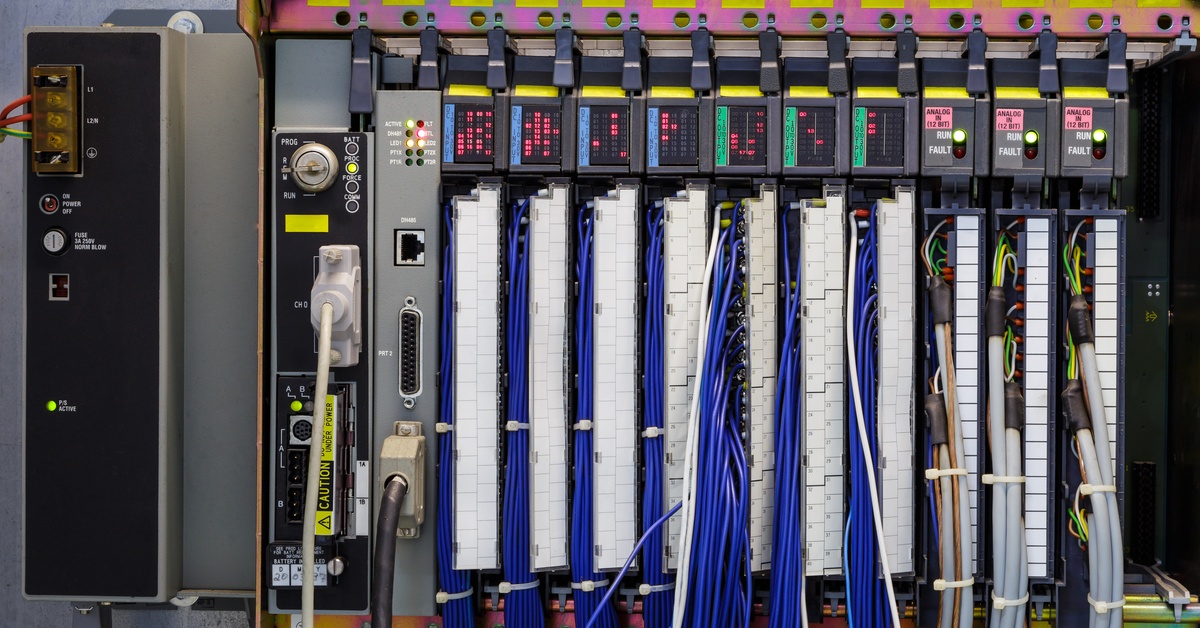 A close-up of a large box with multiple cables, connectors, small digital screens, and plugs aligned in a row.