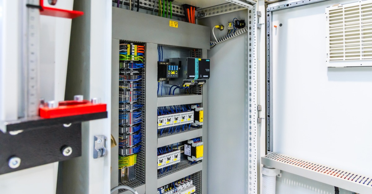 A large white box with multiple cables of different colors, panels, connectors, and coils inside a small room.